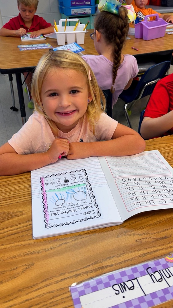 miss Richardson‘s kindergarten student holding or writing in their Weather journal in the classroom