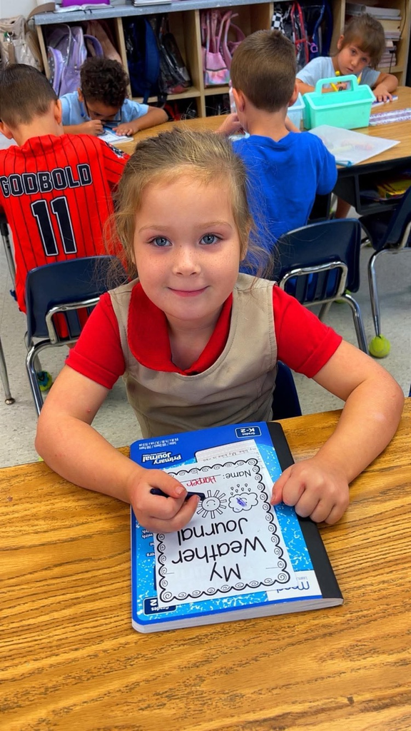miss Richardson‘s kindergarten student holding or writing in their Weather journal in the classroom