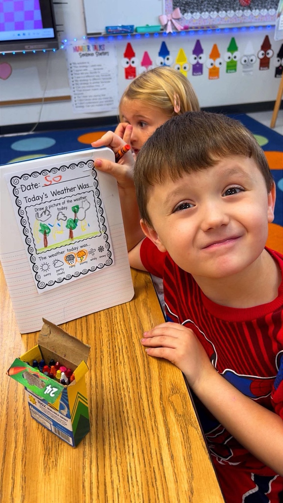 miss Richardson‘s kindergarten student holding or writing in their Weather journal in the classroom