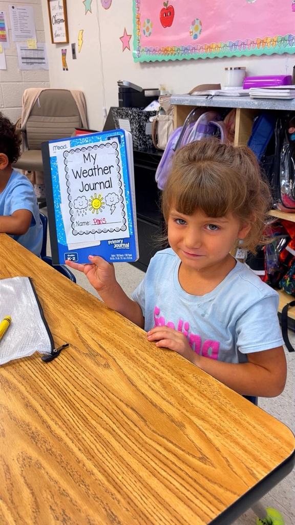 miss Richardson‘s kindergarten student holding or writing in their Weather journal in the classroom
