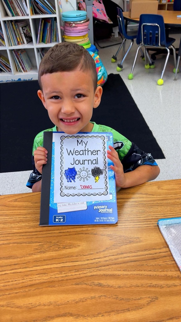 miss Richardson‘s kindergarten student holding or writing in their Weather journal in the classroom