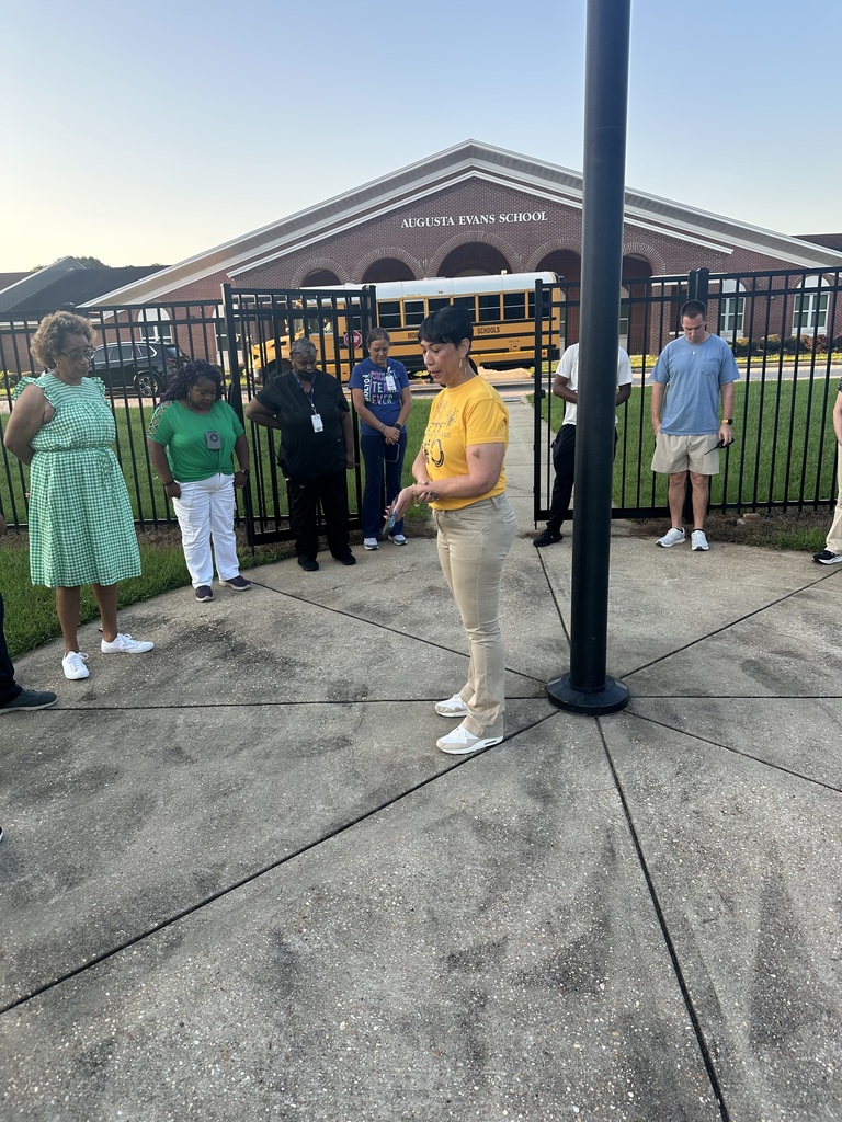 Mrs. Kidd giving a word of encouragement to her staff around the flagpole 
