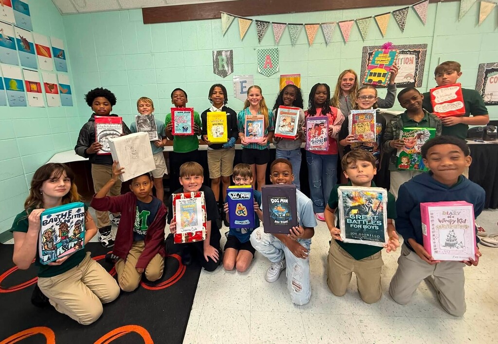 A group of students holding book cover cereal boxes they designed