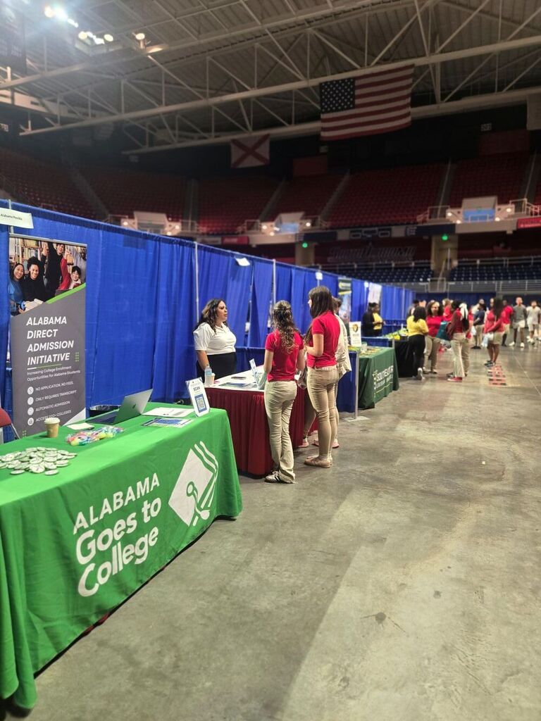 Two girls talking to one of the college representatives.