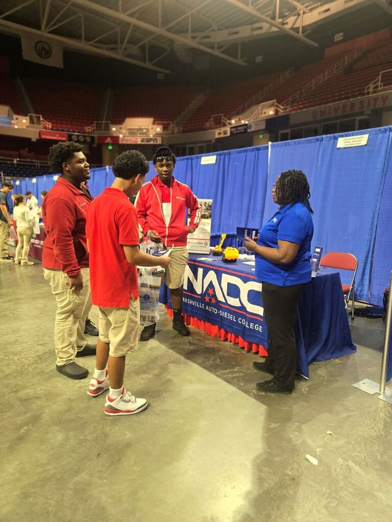 Three boys talking to a college representative.