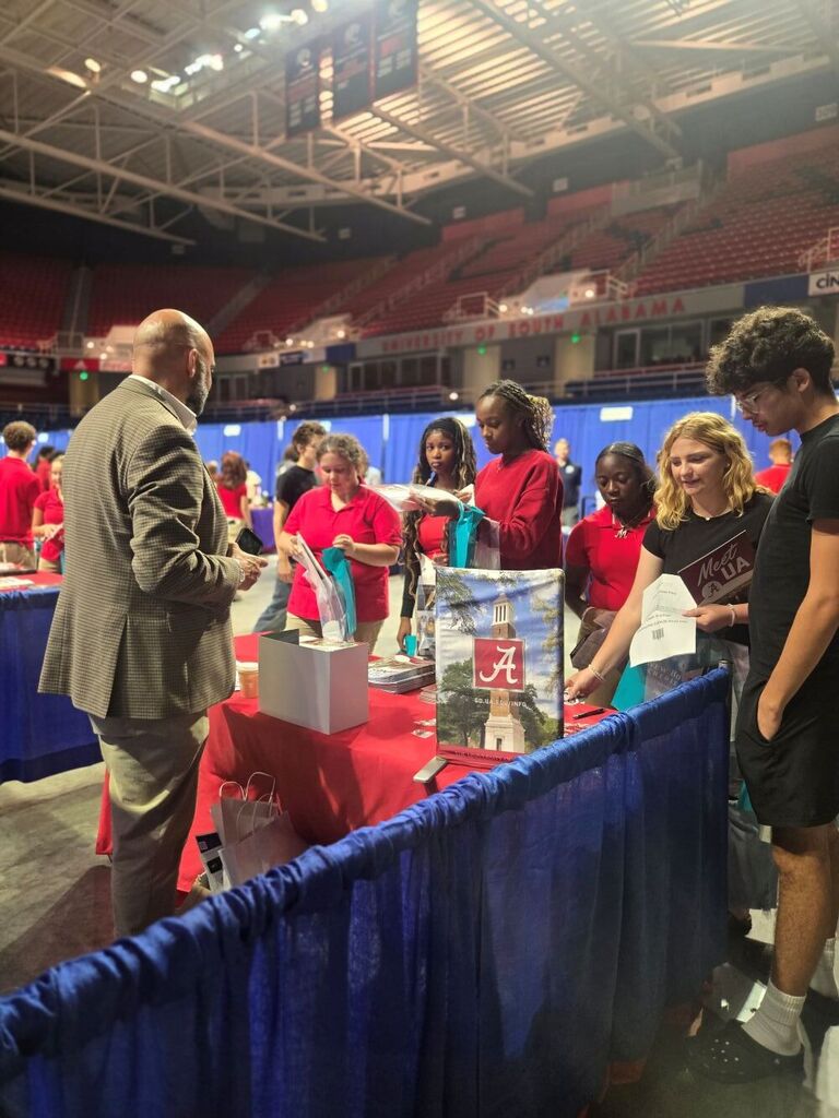 A group of students talking to the University of Alabama representative.