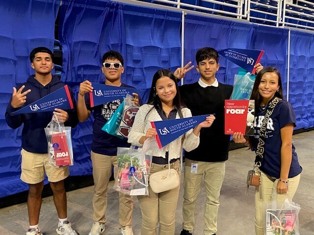 Baker students holding South Alabama pennants and swag bags from colleges
