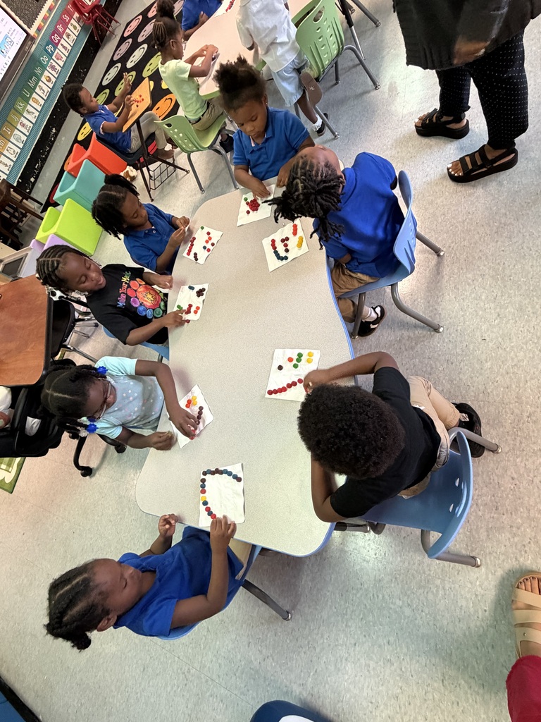 A classroom with students at tables, engaged in an activity with papers and crayons.