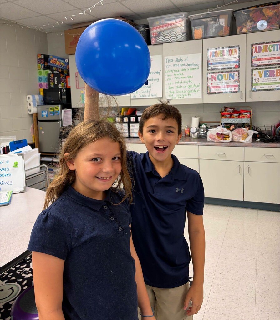A boy holding a balloon over a girl's head to display static electricity