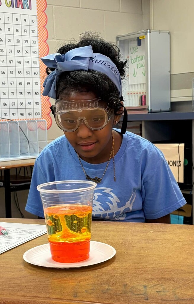 A girl looks at a lava lamp in a plastic cup