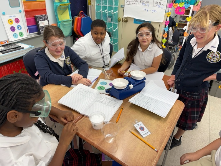 Mrs. Barnes’ fifth-grade students conduct a science experiment by mixing baking soda with a citric acid solution to observe a chemical reaction and learn about the Law of Conservation of Matter.