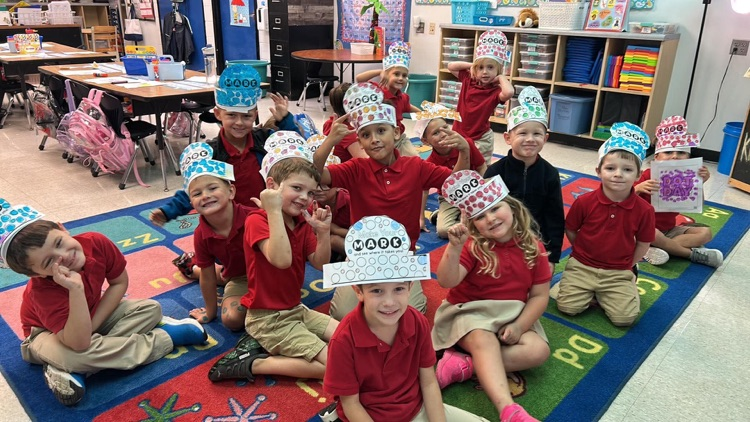 kindergartners wearing their dot hats sitting on a carpet in the classroom