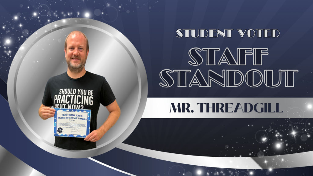 Man holding a certificate with "Student Voted Staff Standout" text. He wears a black t-shirt.