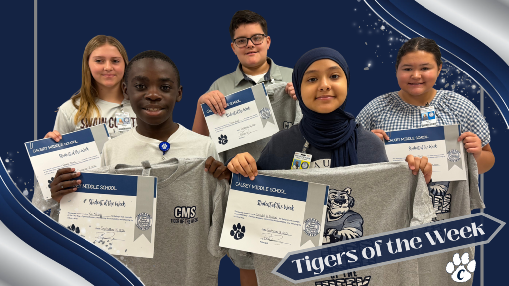 Five students stand together holding certificates. They are wearing white shirts with school emblems. The central student is wearing a hijab.