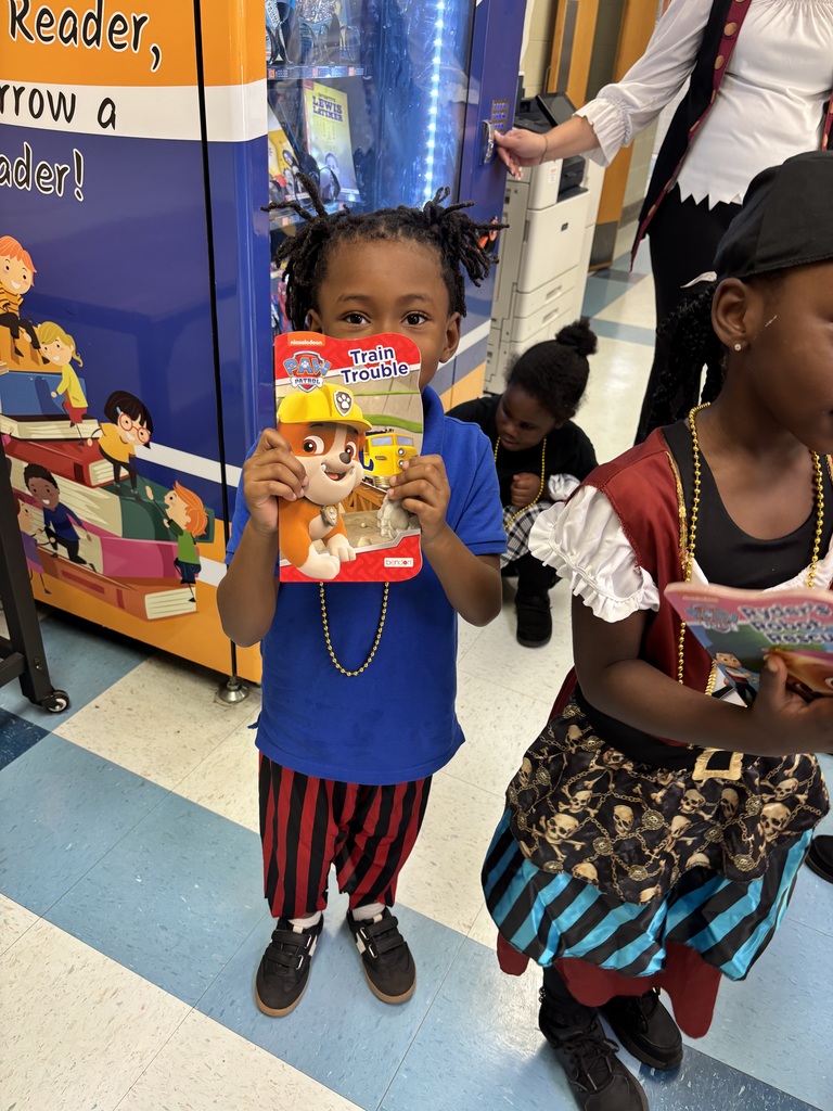 Two children hold books, one dressed in pirate costume, the other in blue. They stand near a vending machine and a person with a backpack.