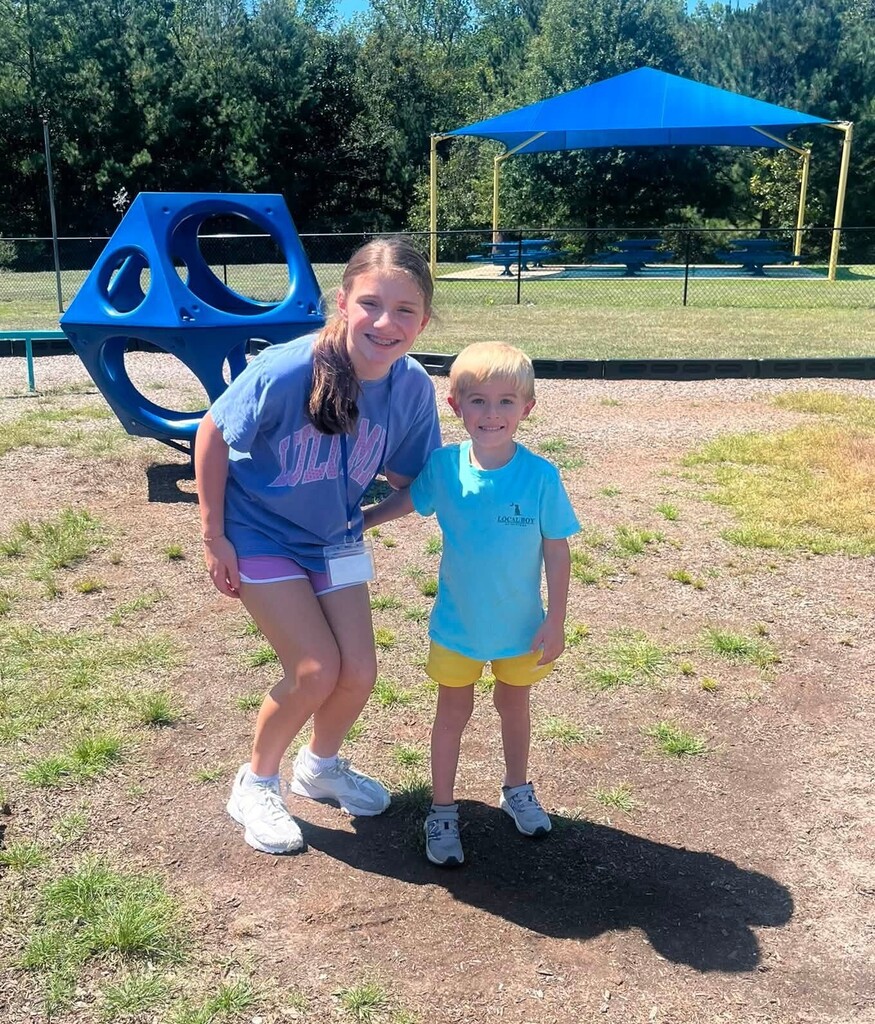 A fifth grader stands with a kindergartener