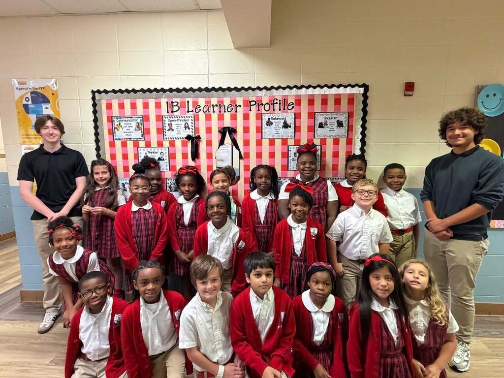 Two high school students stand with a group of elementary students