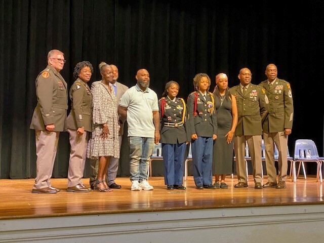 Two JROTC cadets surrounded by instructors and family members