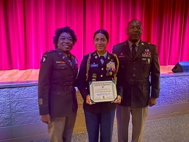 A JROTC cadet stands with two instructors