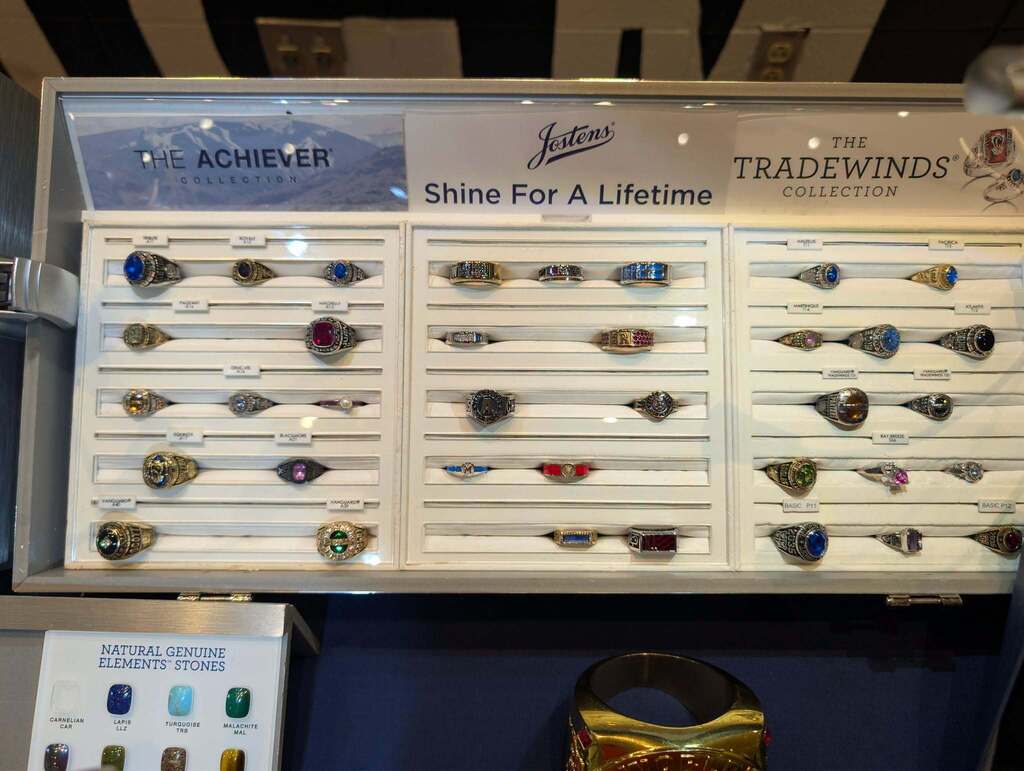 Display case with rows of rings, a sign that reads "Shine For A Lifetime" and "Tradewinds" on a blue background.