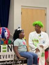 A girl with glasses seated on a chair and a man in a lab coat next to her.