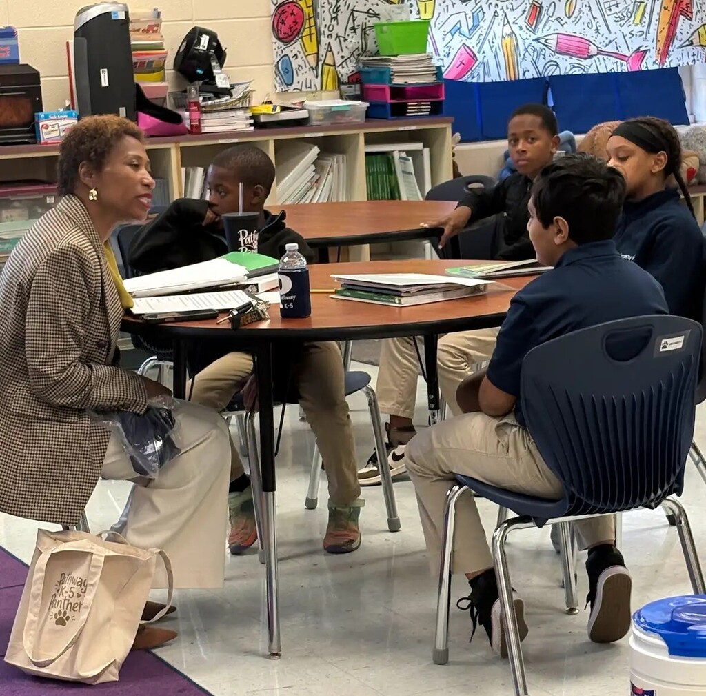 A woman talking to students at a table in a classroom
