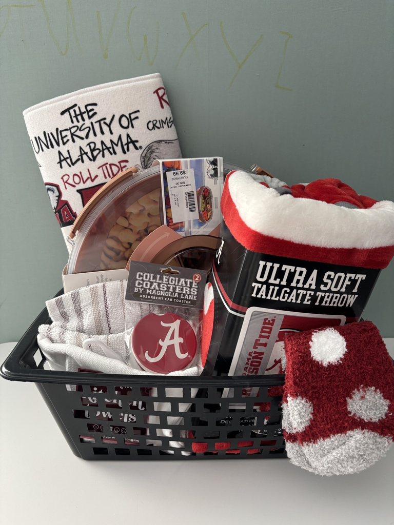 A basket filled with items, including a blanket, towel, and socks, with a sign reading "The University of Alabama Roll Tide".