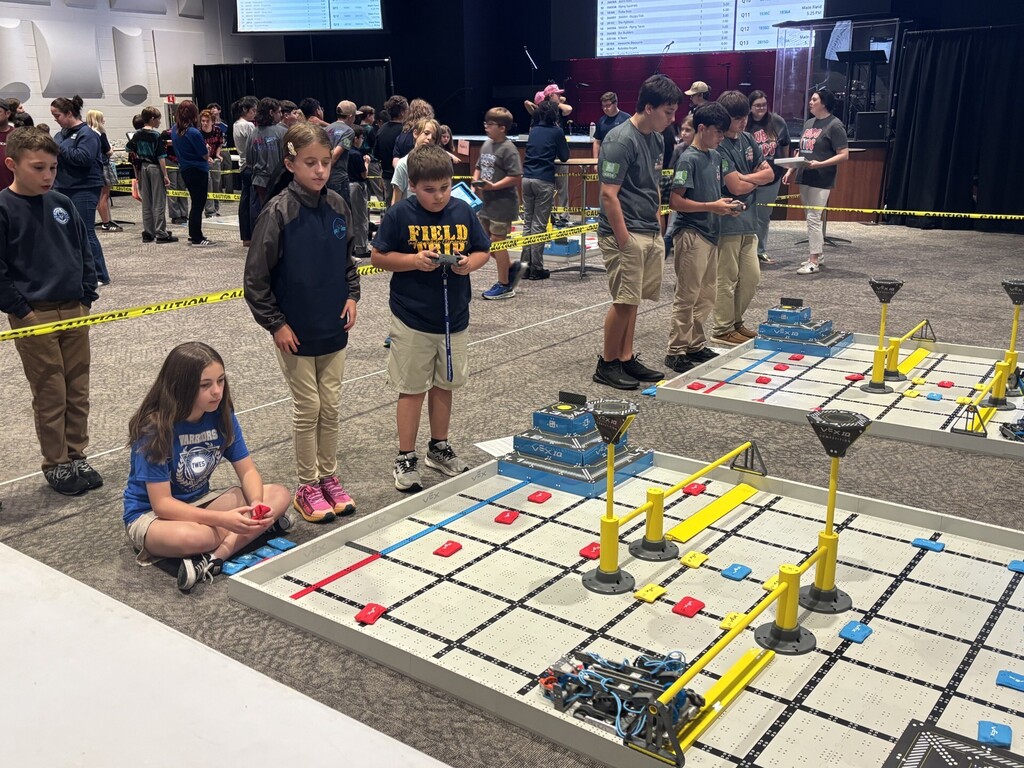 A group of students playing on a large game board with yellow and red markers.