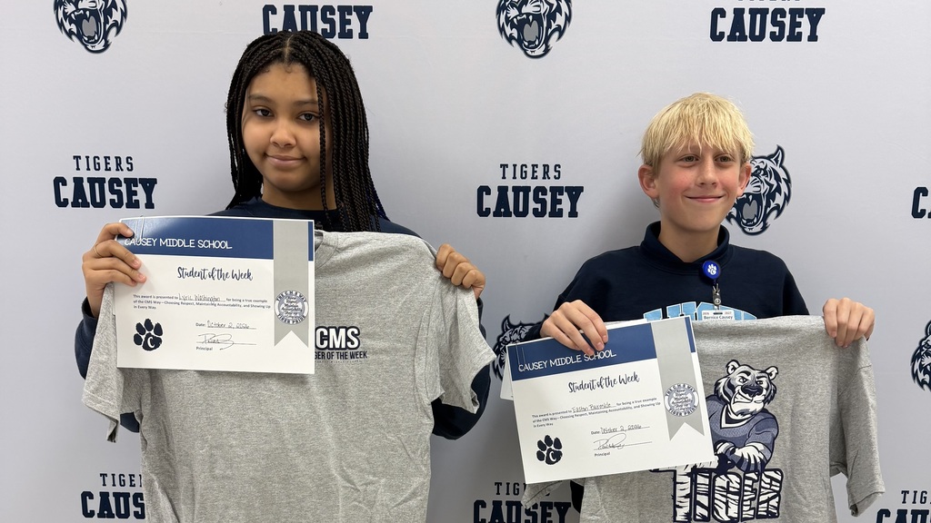Two students hold certificates above their chests. One holds a certificate with text in front of a tiger.