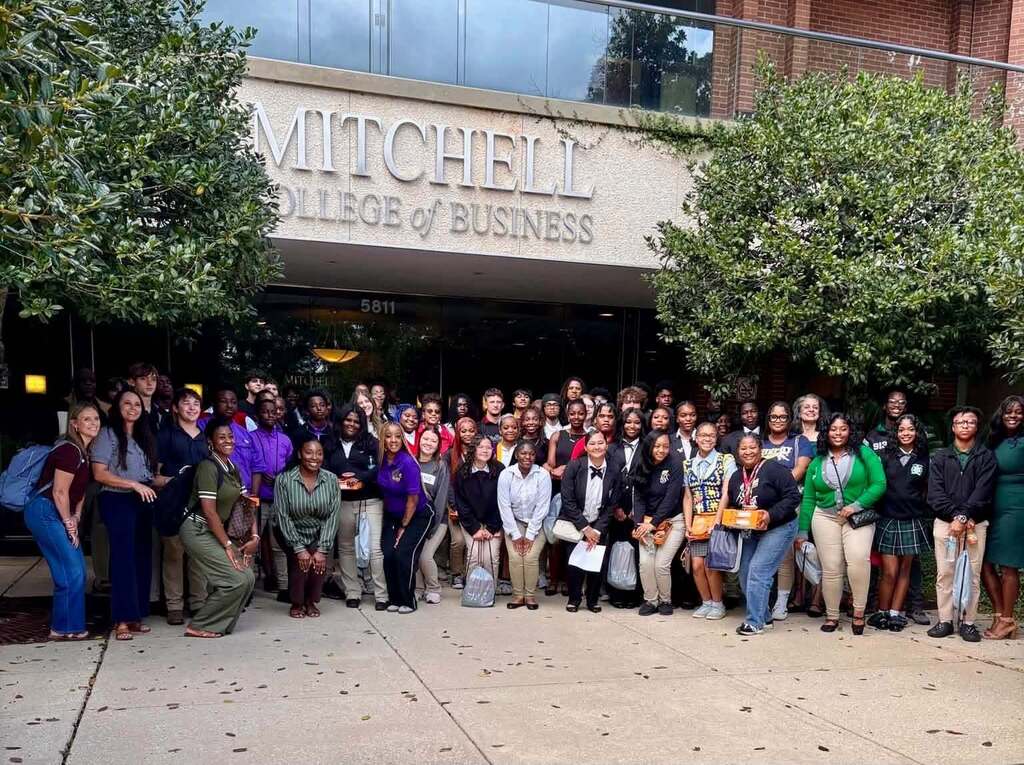 A large group of students stand outside the Mitchell College of Business at South Alabama