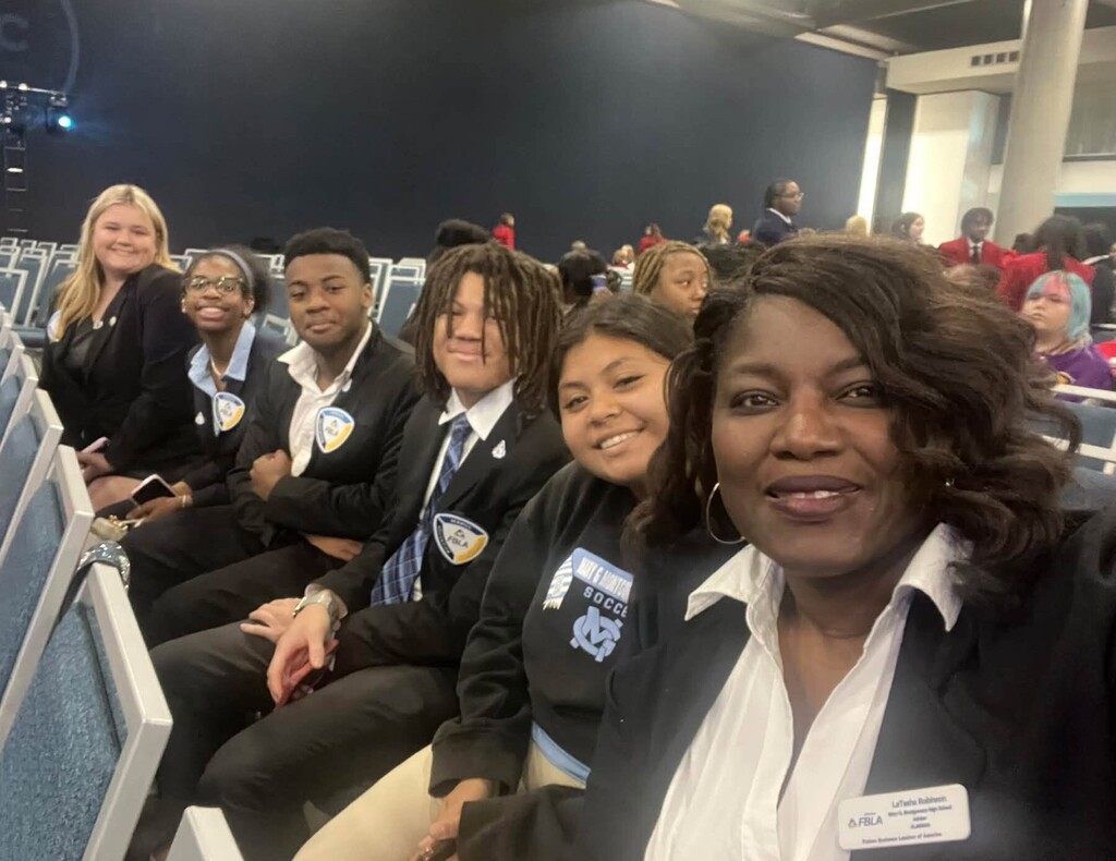 A teacher and a group of students seated in a row