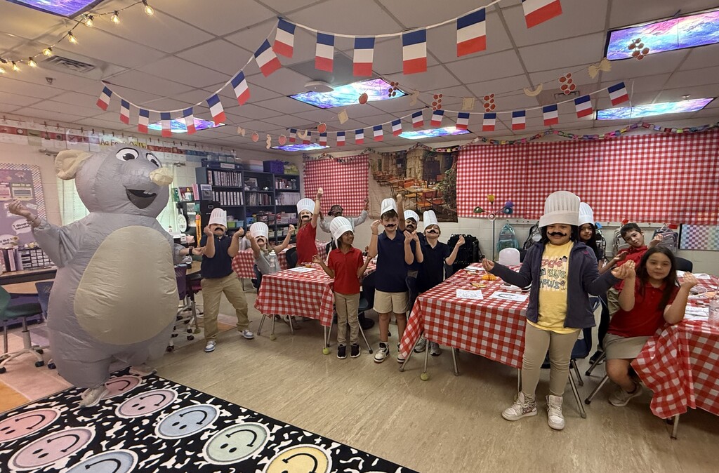 Students in chef's hats in a classroom with a teacher in an inflatable elephant costume