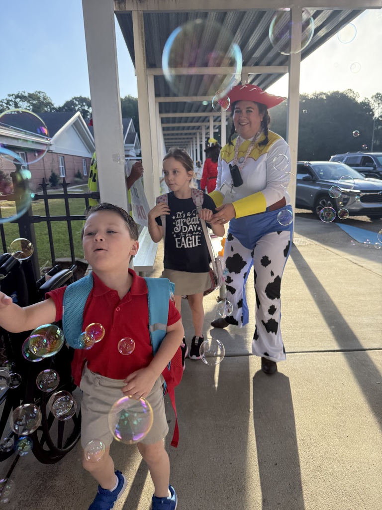 Two students walk through bubbles with a teacher dressed as Jessie from Toy Story