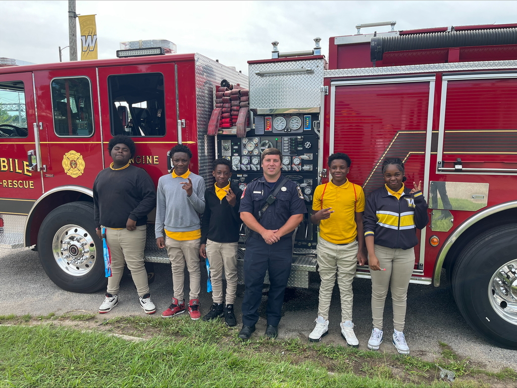 A firefighter and five students standing by a fire truck