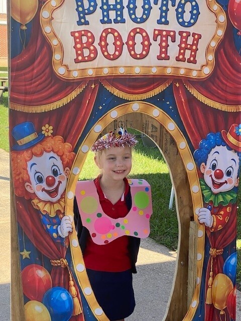 A student poses in a clown-themed "photo booth" cutout