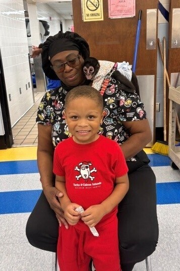 A student poses with a cafeteria worker who has a monkey on her shoulder