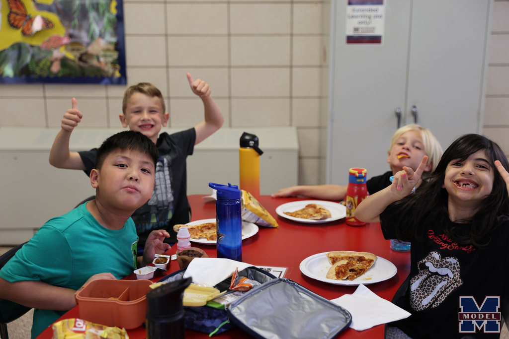 eating pizza and smiling at lunch table
