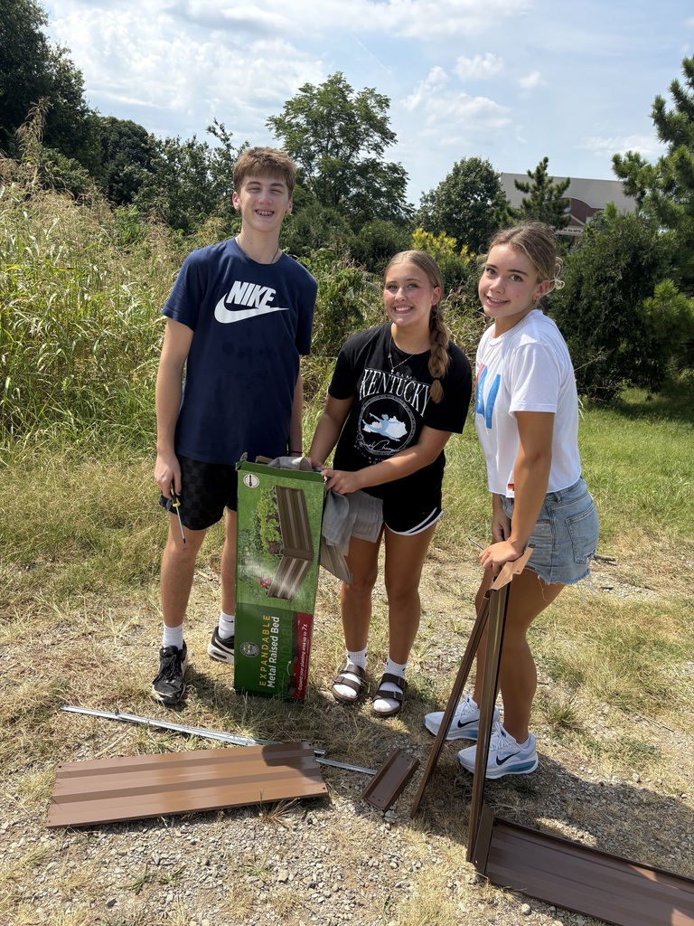 students smiling while building flower bed