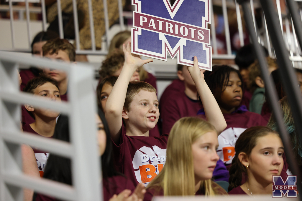 student holding Model Patriots logo sign in crowd