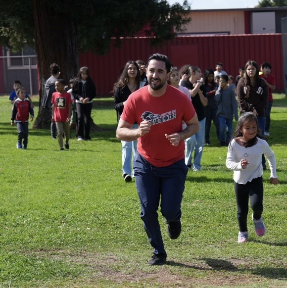 Robertson Road Elementary School Principal Guillermo Lopez Romo runs with students during a Friday fun run