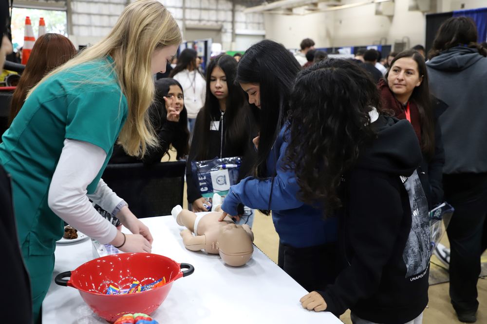 A high school student in the Health Science CTE program demonstrates an activity to eighth graders at the Inspire Youth, Inspire Dreams Expo