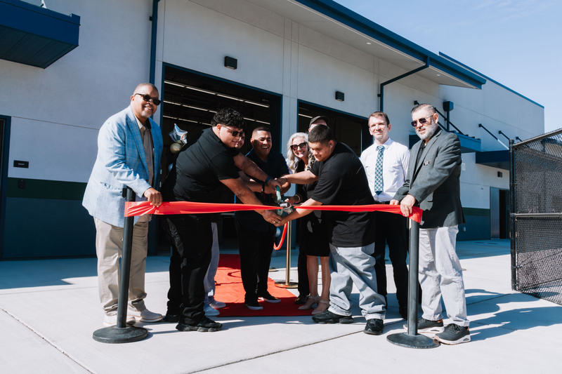 Excited people cut red ribbon for unveiling of new facility