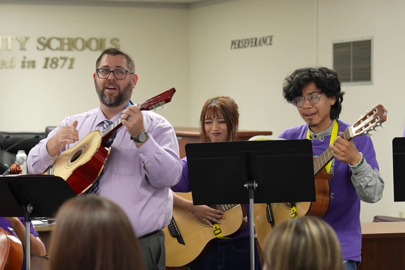 Mariachi Jardin Morado teacher and students playing stringed instruments at board meeting