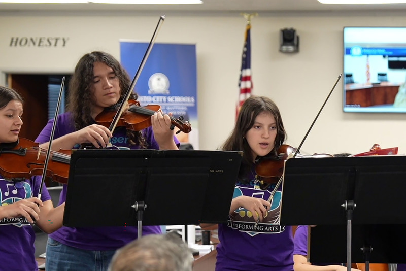 Mariachi Jardin Morado teacher and students playing stringed instruments at board meeting