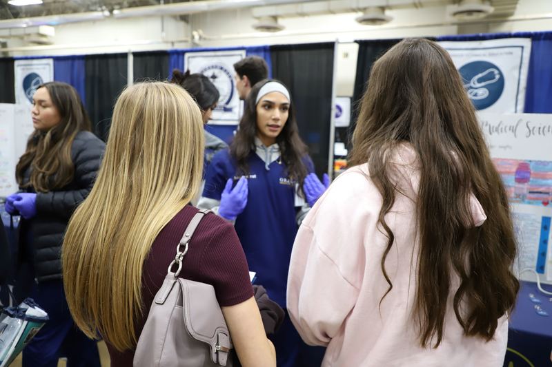 CTE student talking with eighth graders at event.