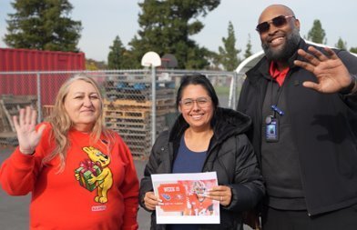 MCS staff member wins 49er football game tickets as part of Be The Change, holds up ticket voucher