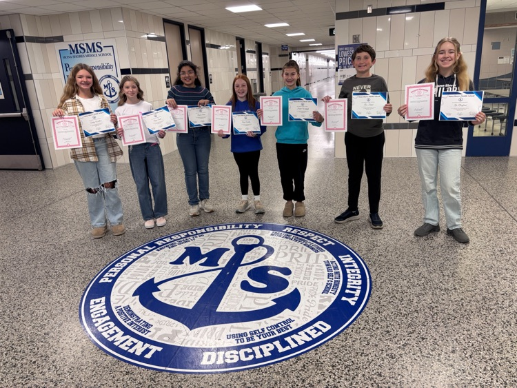October students of the month in the foyer of the school with their certificates