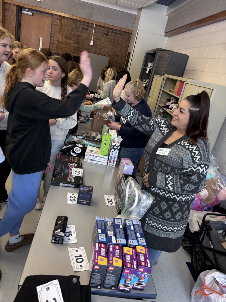 students high-fiving a parent crew volunteer at the store