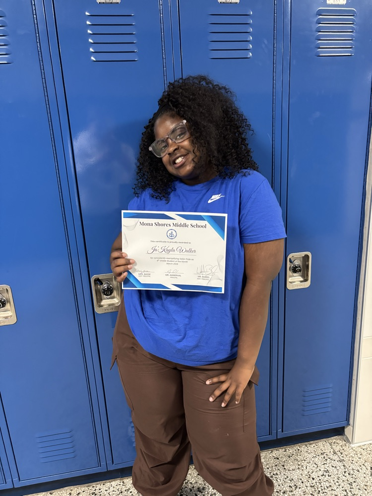 student of the month posing with certificate by blue lockers 