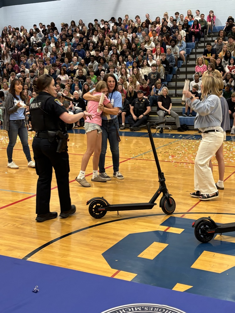 student winning electric scooter and getting a hug from a teacher